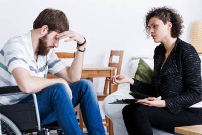 Home assistant talking with depressed invalid patient in wheelchair